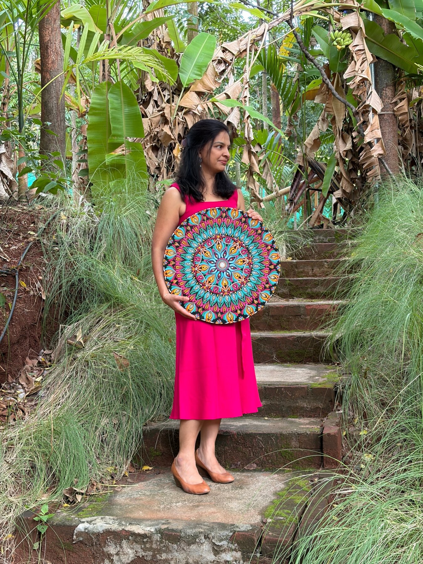 Nandhini holding a large handcrafted dot mandala outdoors